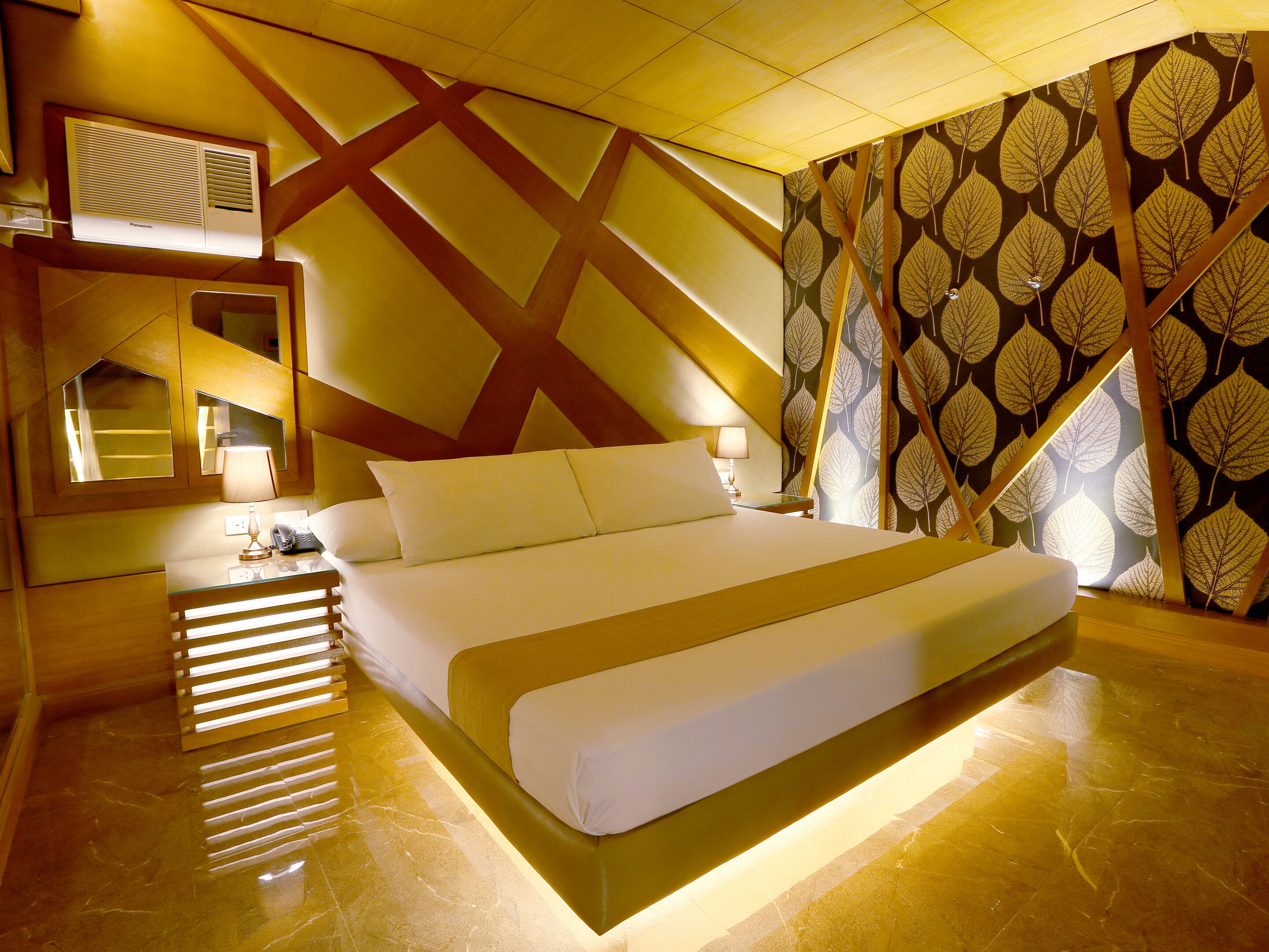 Habitació d'hotel moderna amb un llit gran, una tauleta de nit, una làmpada i un ventilador de sostre.