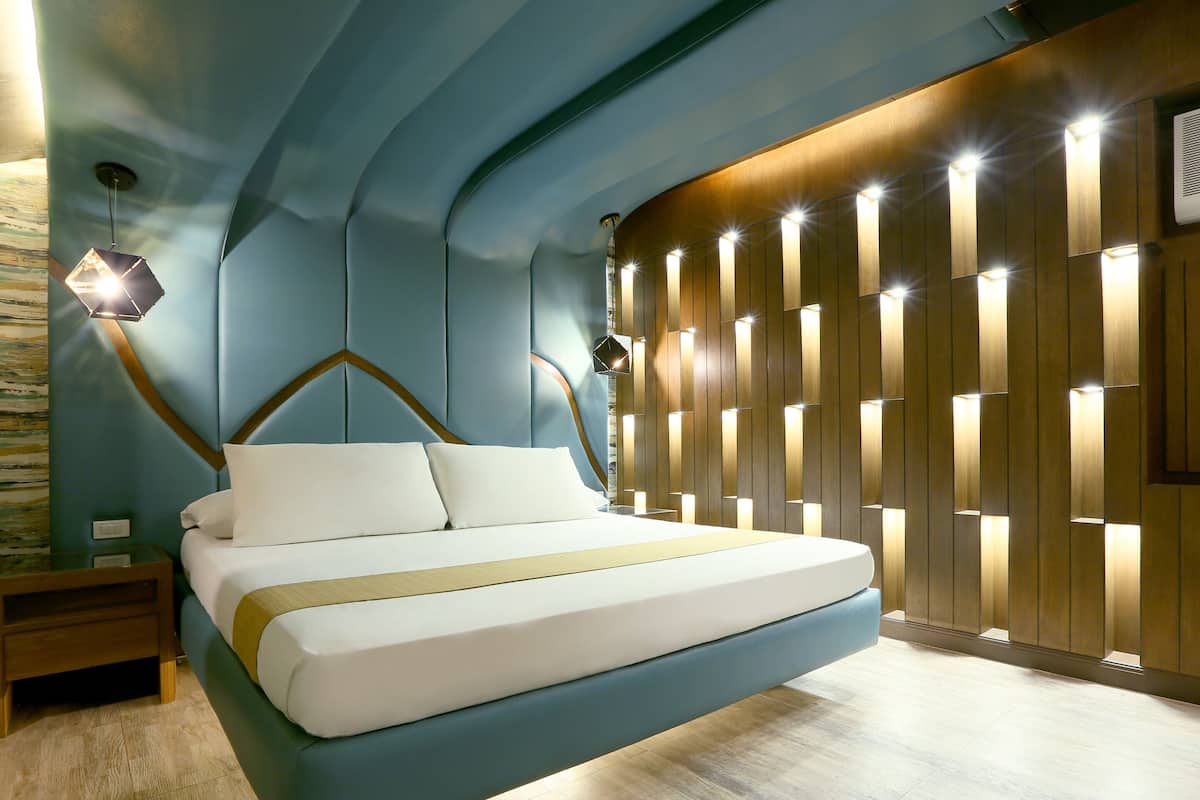 A modern bedroom with a bed, nightstands, and a unique wall design.