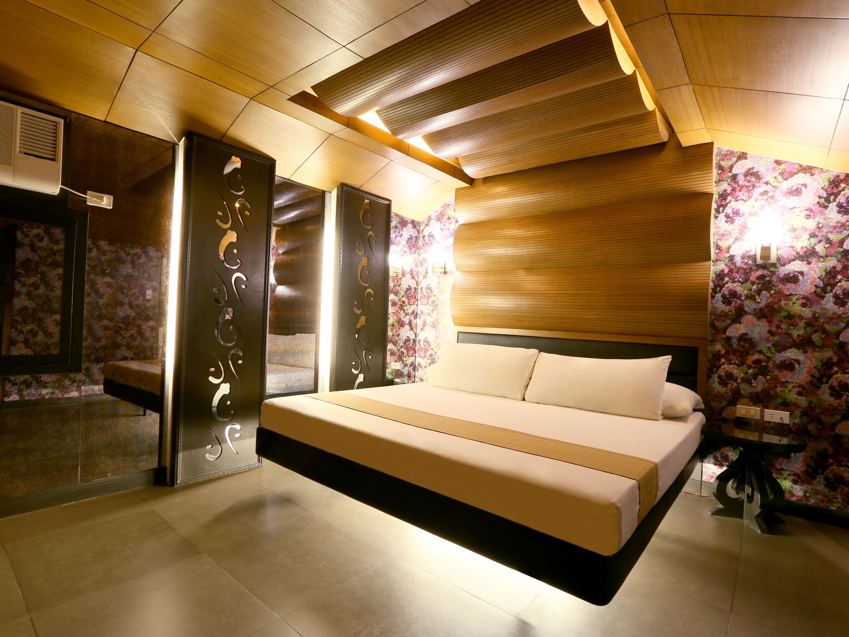A modern bedroom with a large bed, wooden ceiling panels, and floral wallpaper.