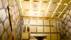 A modern room with a geometric ceiling design, a central table, a sofa, and a patterned wall. - Hotel Ava Malate, Manila (Manila)