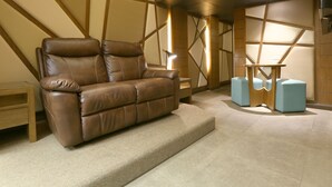 A modern living room with a brown leather sofa, a wooden coffee table, and a blue ottoman. - Hotel Ava Malate, Manila (Manila)