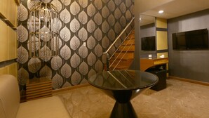 A modern bathroom with a leaf-patterned wallpaper, a glass-top table, and a wooden bench. - Hotel Ava Malate, Manila (Manila)