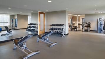 Un gimnasio moderno con equipamiento de levantamiento de pesas, mancuernas y máquinas de cardio.