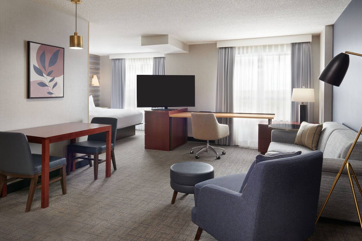 Une chambre d’hôtel comprenant un lit, un bureau, une télévision, un canapé et un coin repas.