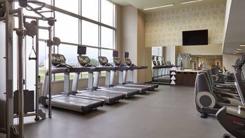 A gym with treadmills, weight machines, and a large window offering a view of the outdoors.