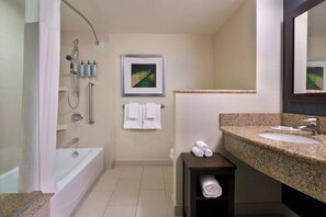 Un baño con bañera, ducha, lavabo y un cuadro en la pared.