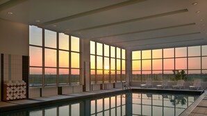 A swimming pool with a sunset view, tiled walls, and lounge chairs. - Courtyard by Marriott Calgary Airport (Calgary)