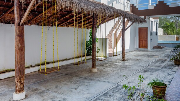 Un'area esterna coperta con tetto di paglia, una scala e un edificio bianco con porta in legno.