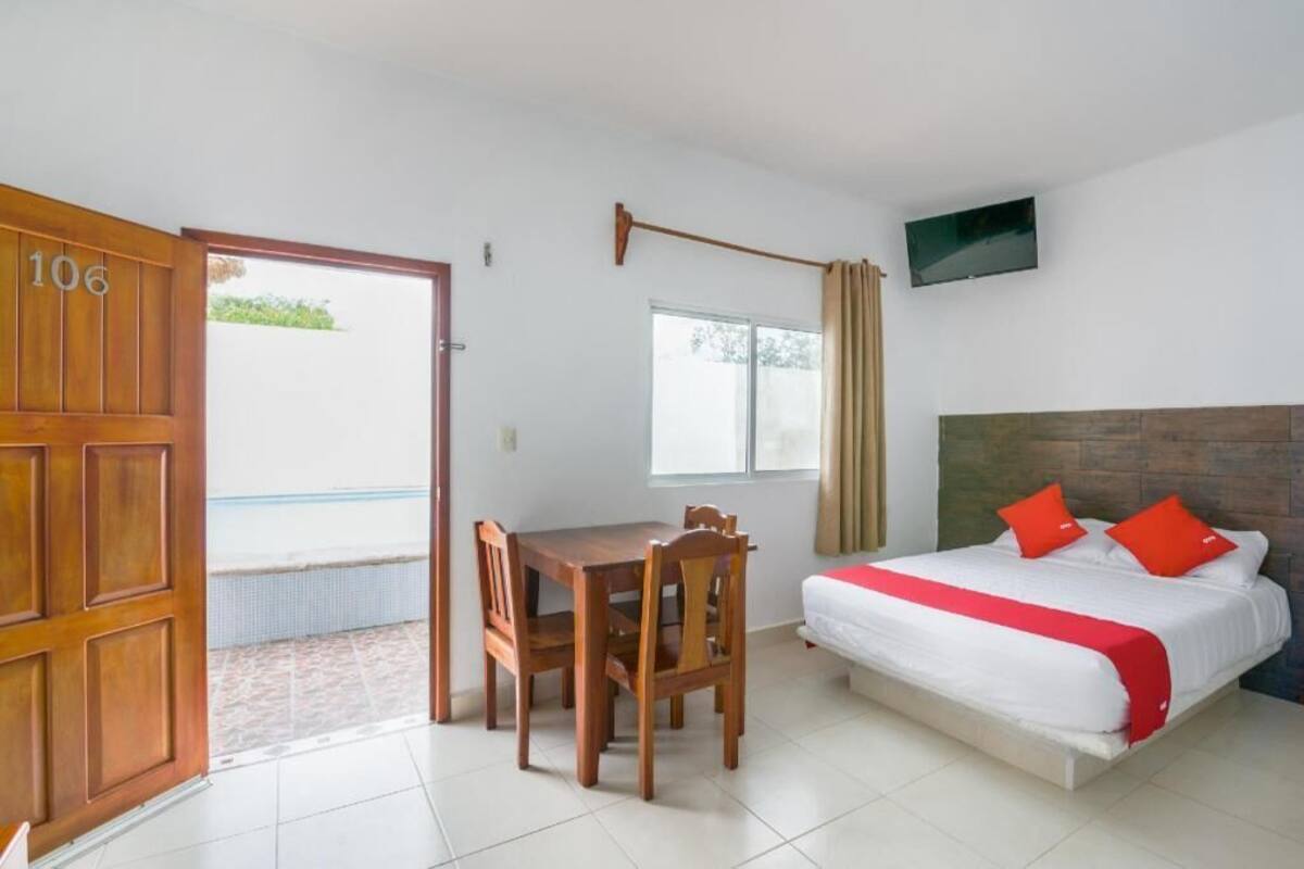 A room with a bed, a table with chairs, a TV on the wall, and a door with the number 106.