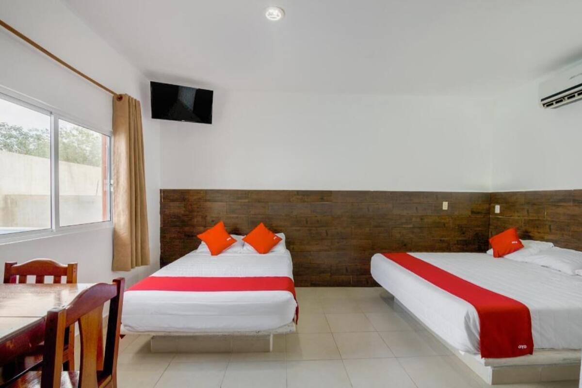 A hotel room with two beds, a TV, and a window with curtains.