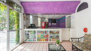 Una stanza con una vetrina piena di snack, un tendone viola e un’area salotto con un divano floreale.