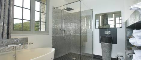 Un baño moderno con una bañera grande, una ducha con mampara de vidrio y un lavamanos con espejo.