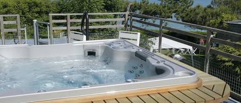 A hot tub on a wooden deck with a view of the sea.