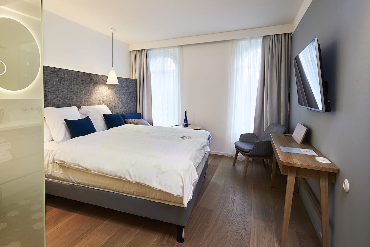 Una habitación de hotel moderna con una cama grande, un escritorio y un televisor.