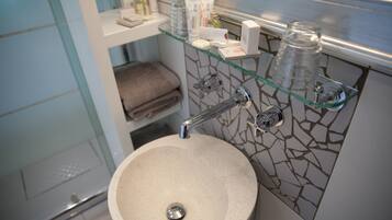 A bathroom with a round sink, glass shelves, and a towel rack.