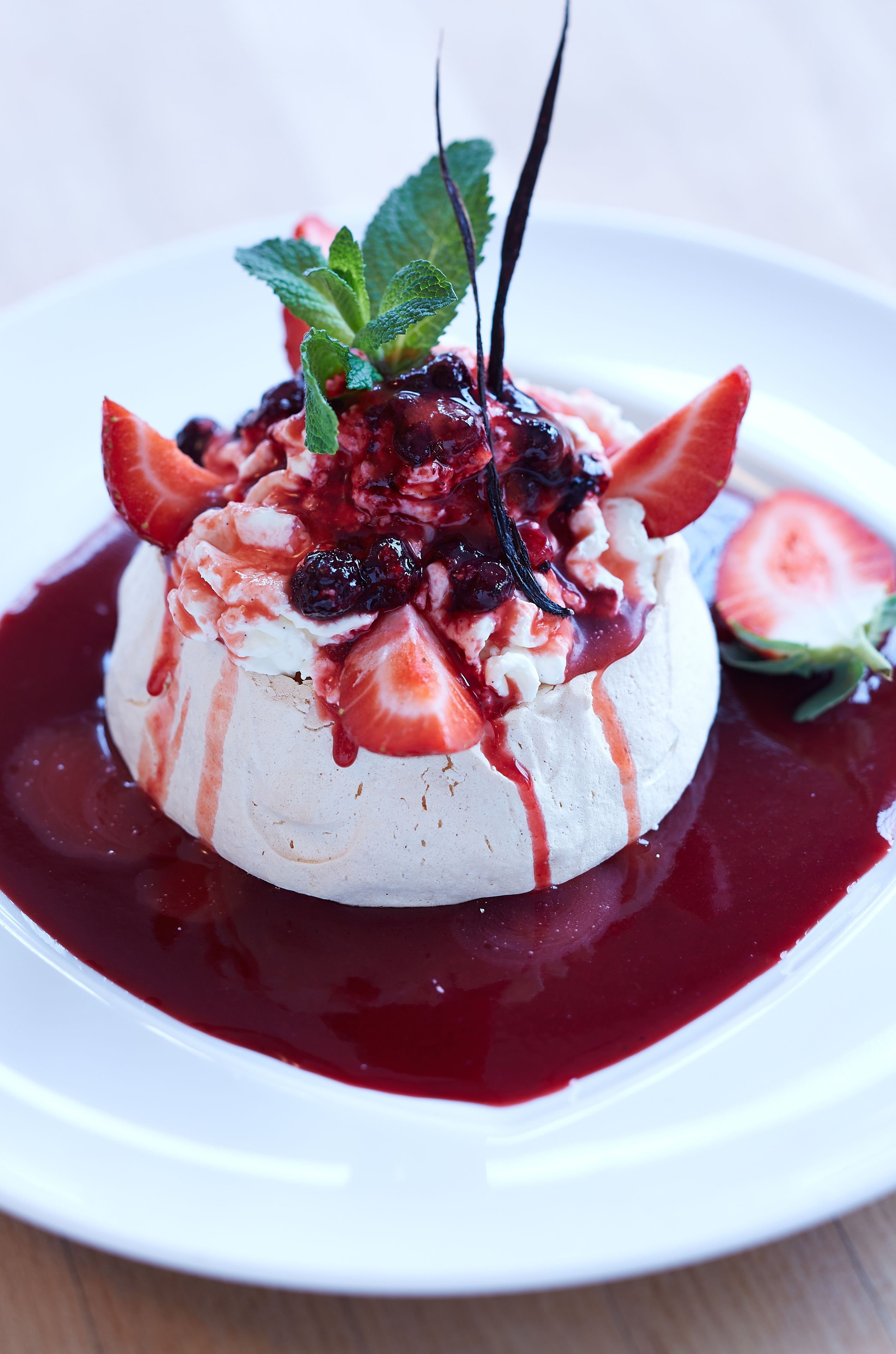 A dessert on a white plate with a berry sauce.