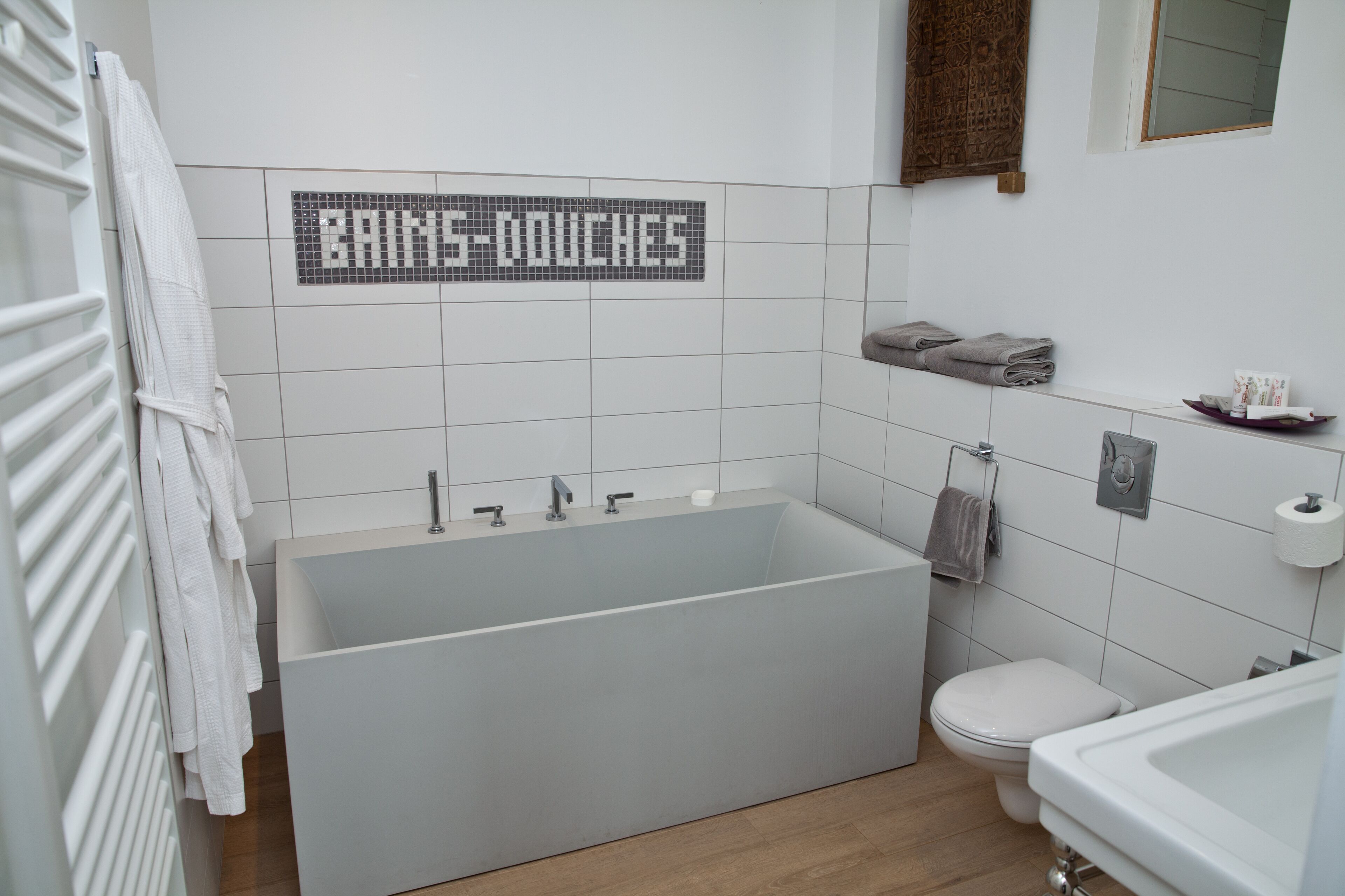 A modern bathroom with a large bathtub, a toilet, and a towel rack.
