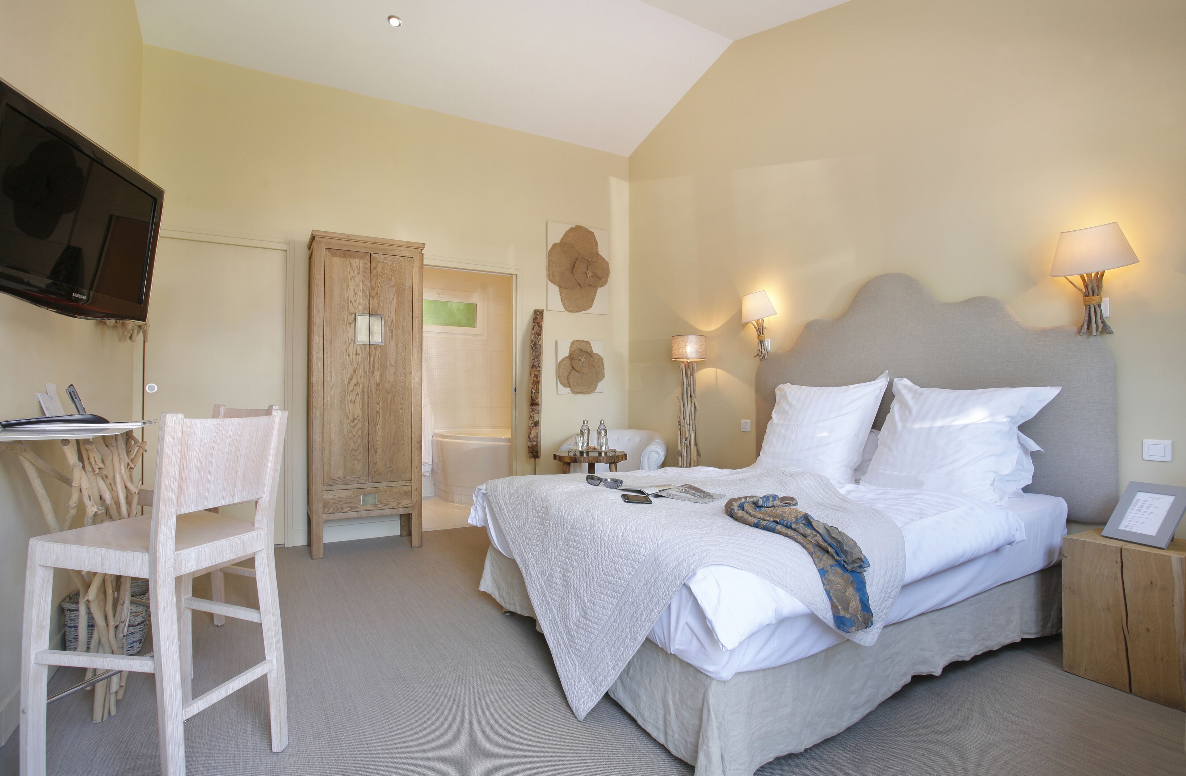 A bedroom with a bed, bedside table, chair, and a television mounted on the wall.