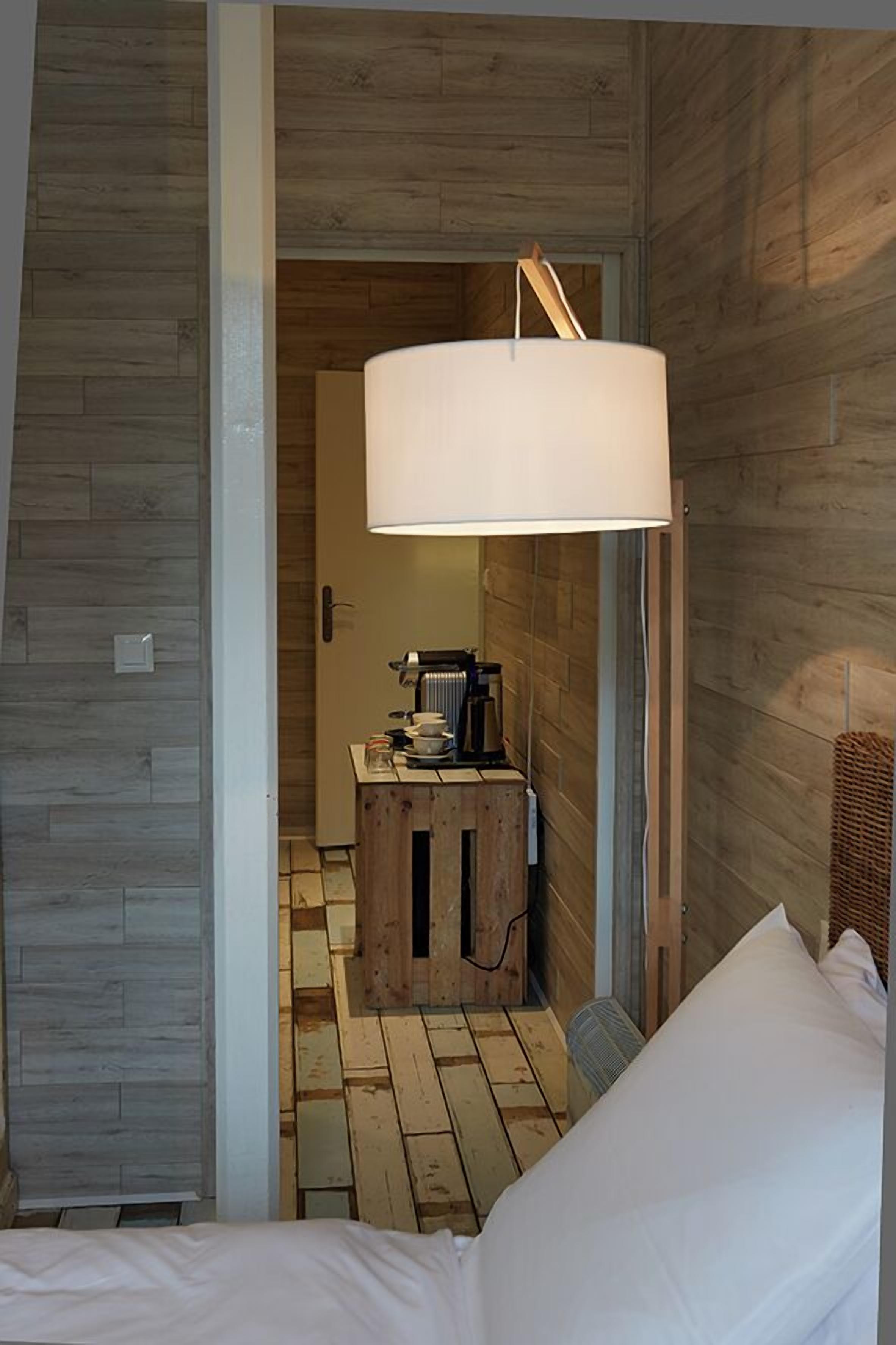 A compact room with a bed, a wooden cabinet, and a hanging lamp.