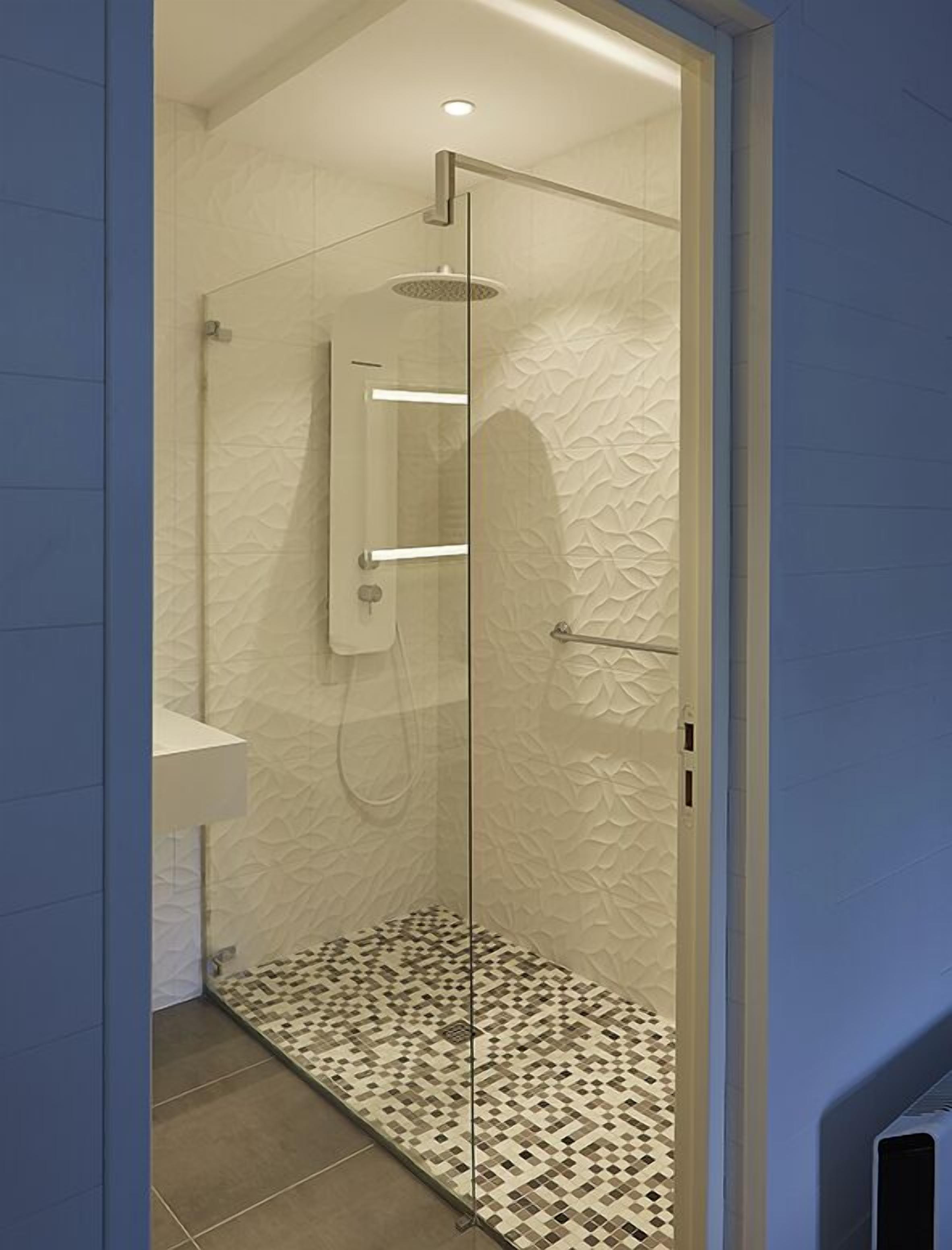 Eine begehbare Dusche mit Glaswänden, einer Regendusche, einem Handbrausegerät und einer fest installierten Bedienkonsole.