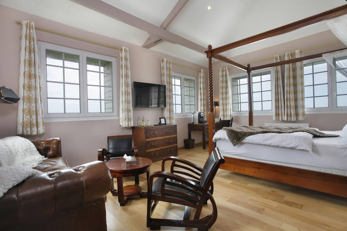 Un dormitorio con cama con dosel, un escritorio de madera, una silla, un televisor y un aparador.