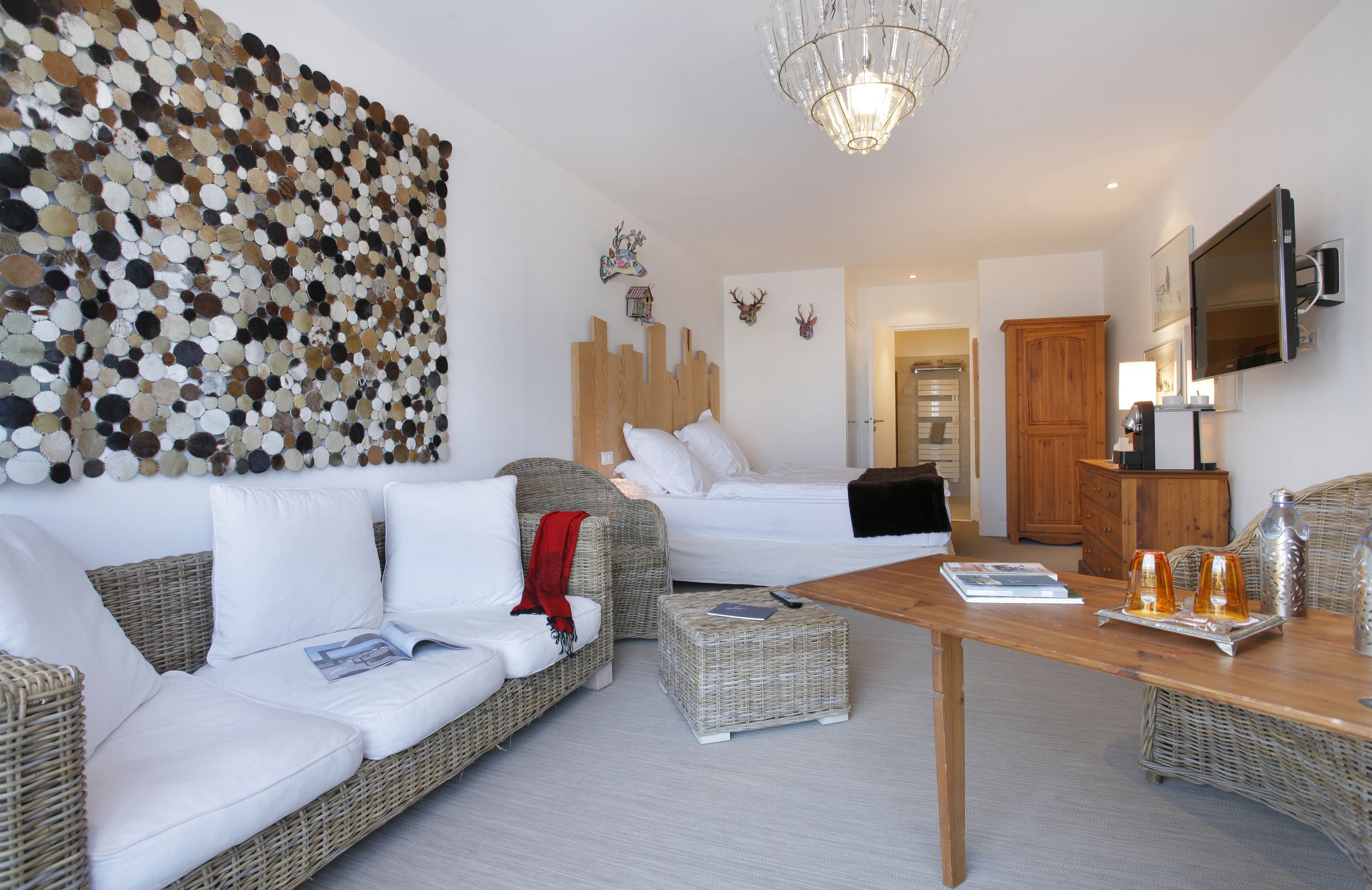 Une chambre d’hôtel moderne avec une grande œuvre d’art murale, une tête de lit en bois, un lit, un canapé, une table basse et un téléviseur.