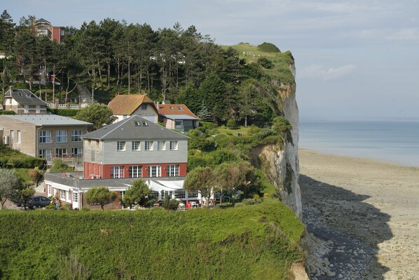 A coastal property with a prominent cliff overlooking the beach, featuring multiple buildings with varying architectural styles. - Le Cise, The Originals Relais (Ault)