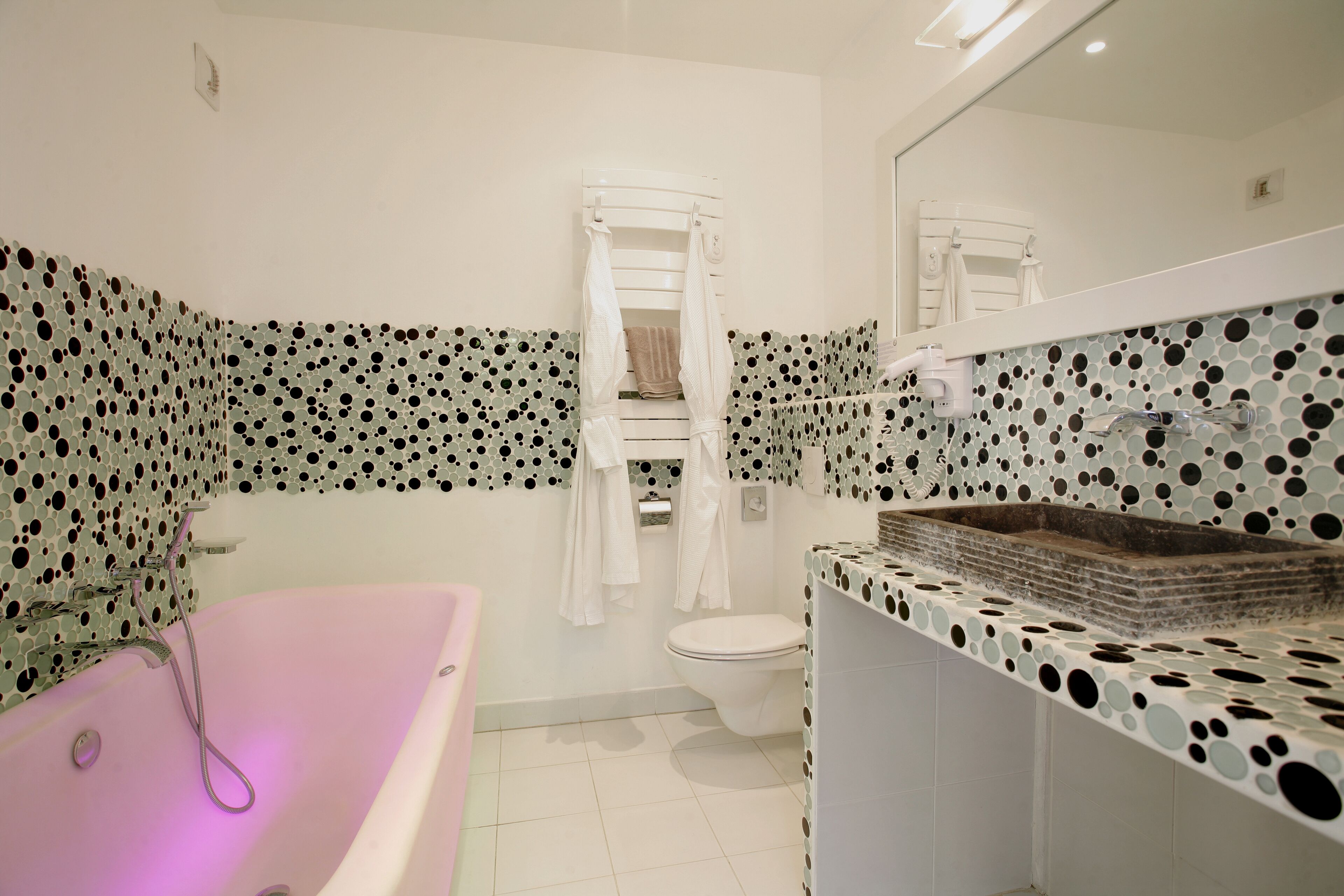 Une salle de bain avec une baignoire sur pieds, des toilettes et un lavabo avec un dosseret de carrelage à pois.