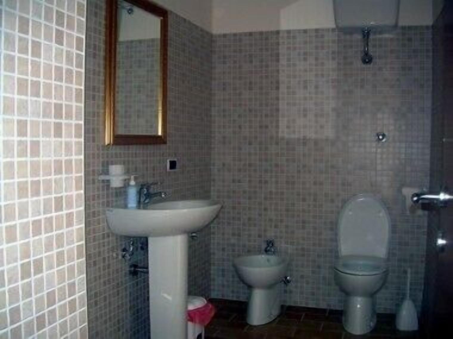 A bathroom with a sink, bidet, and toilet.