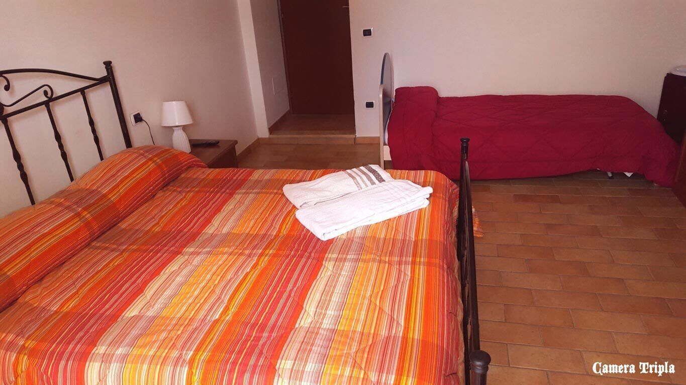 Ein Zimmer mit einem Bett, einem roten Sofa, einer Lampe und einer Tür zu einem anderen Raum.
