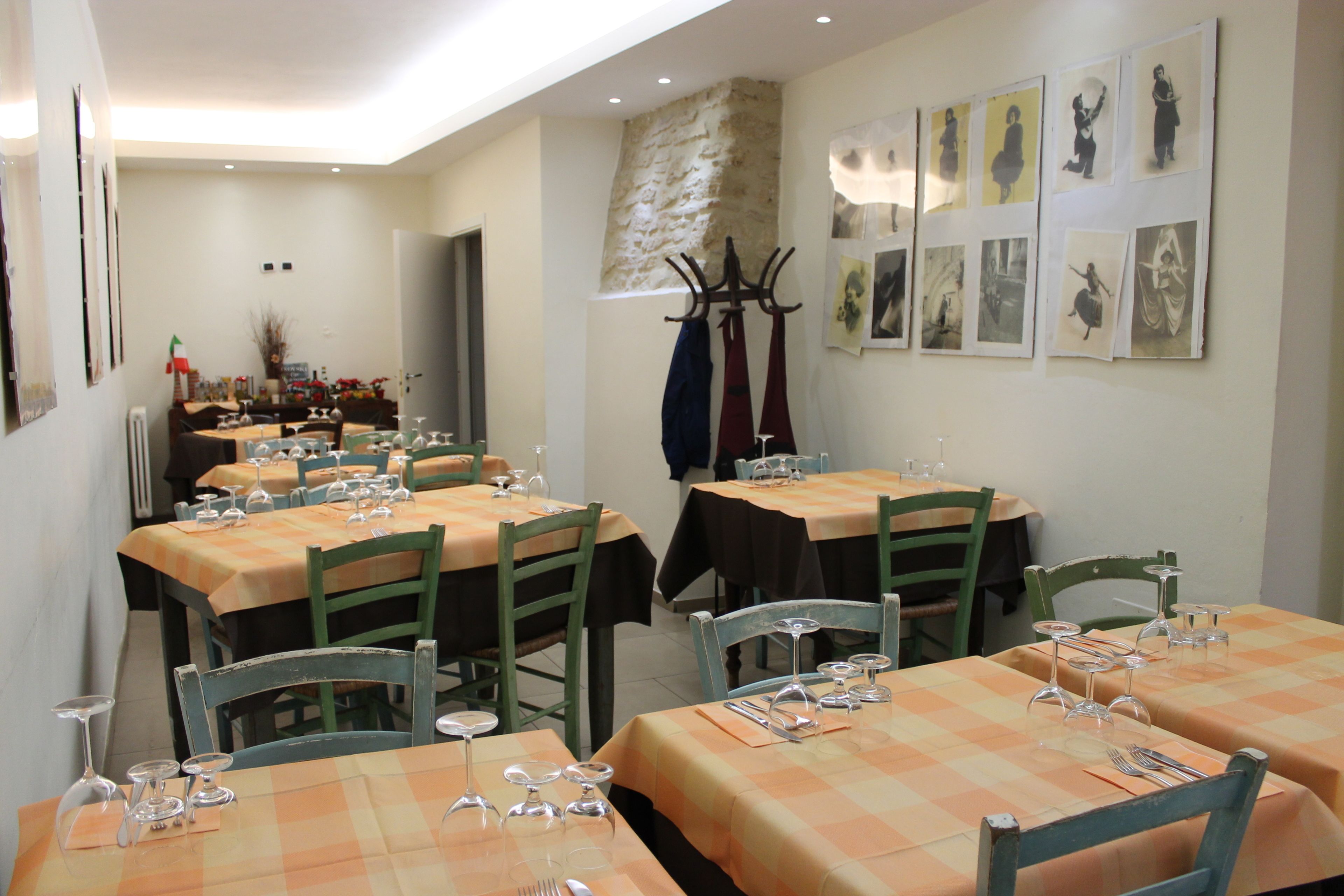 A dining area with tables set for multiple people, chairs, and a coat rack.