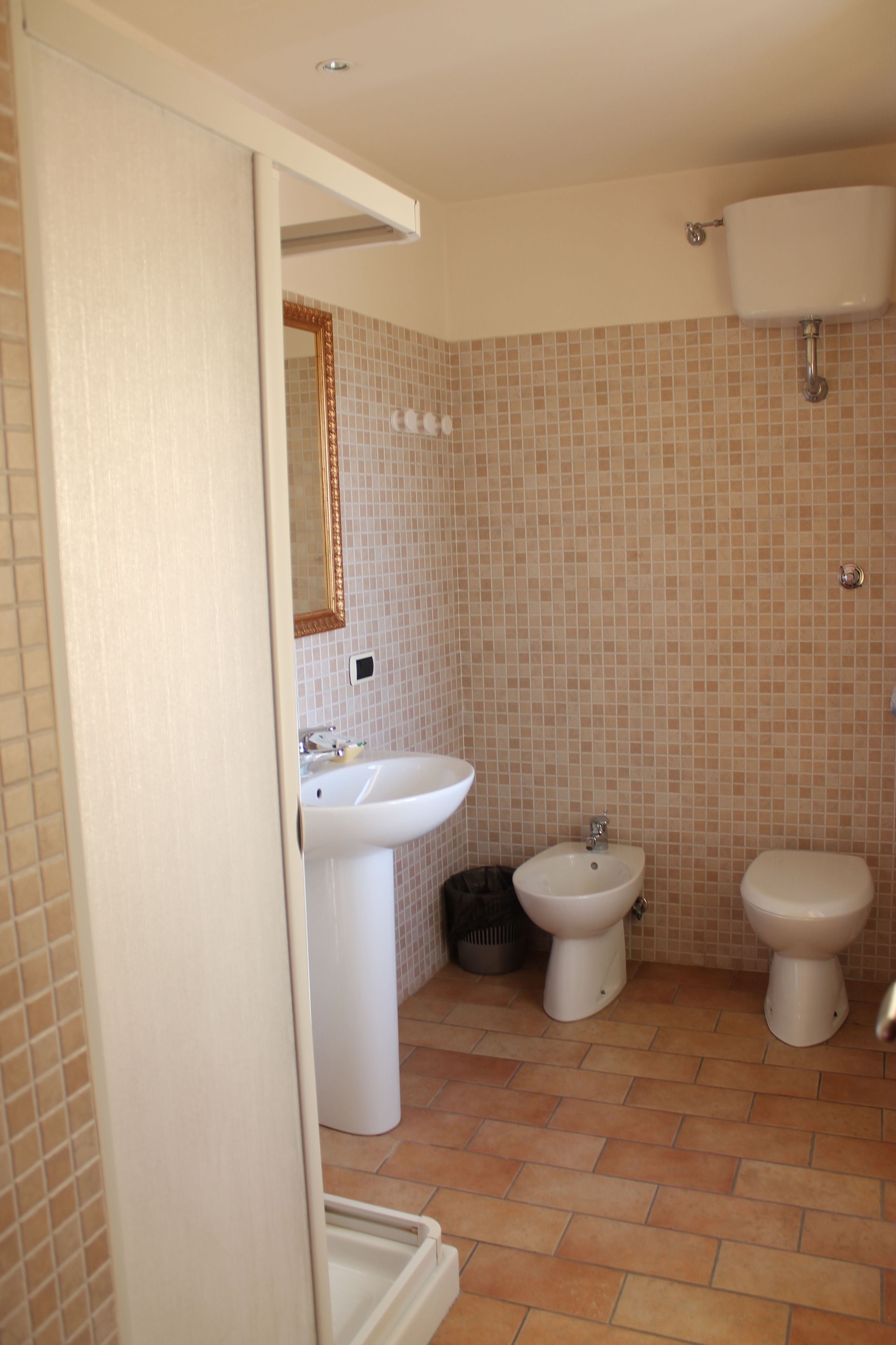 Une salle de bain équipée d’un lavabo, d’un bidet, de toilettes et de murs carrelés.