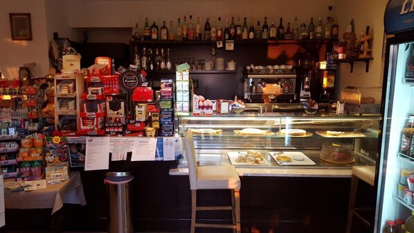 A bakery with a display case of pastries, shelves of bottled beverages, and various packaged goods. - Locanda Fosca Umbra (Narni)