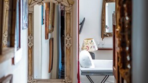 A hallway with a checkered floor, a mirror with a floral design, and a bed with a floral-patterned pillow. - Ibiza Boutique Guest House (Ibiza Town)