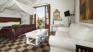 A room with a bed, a white sofa, a checkered floor, a chandelier, and a large painting on the wall. - Ibiza Boutique Guest House (Ibiza Town)
