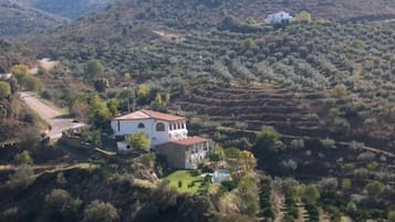 Una villa blanca con techo rojo, rodeada de campos escalonados y colinas.