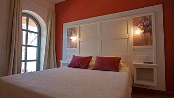 A bedroom with a large bed, a window with curtains, and a wall with a decorative panel.