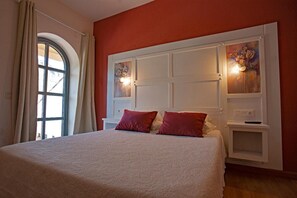 Une chambre à coucher avec un grand lit, une fenêtre avec des rideaux et un mur orné d’un panneau décoratif.