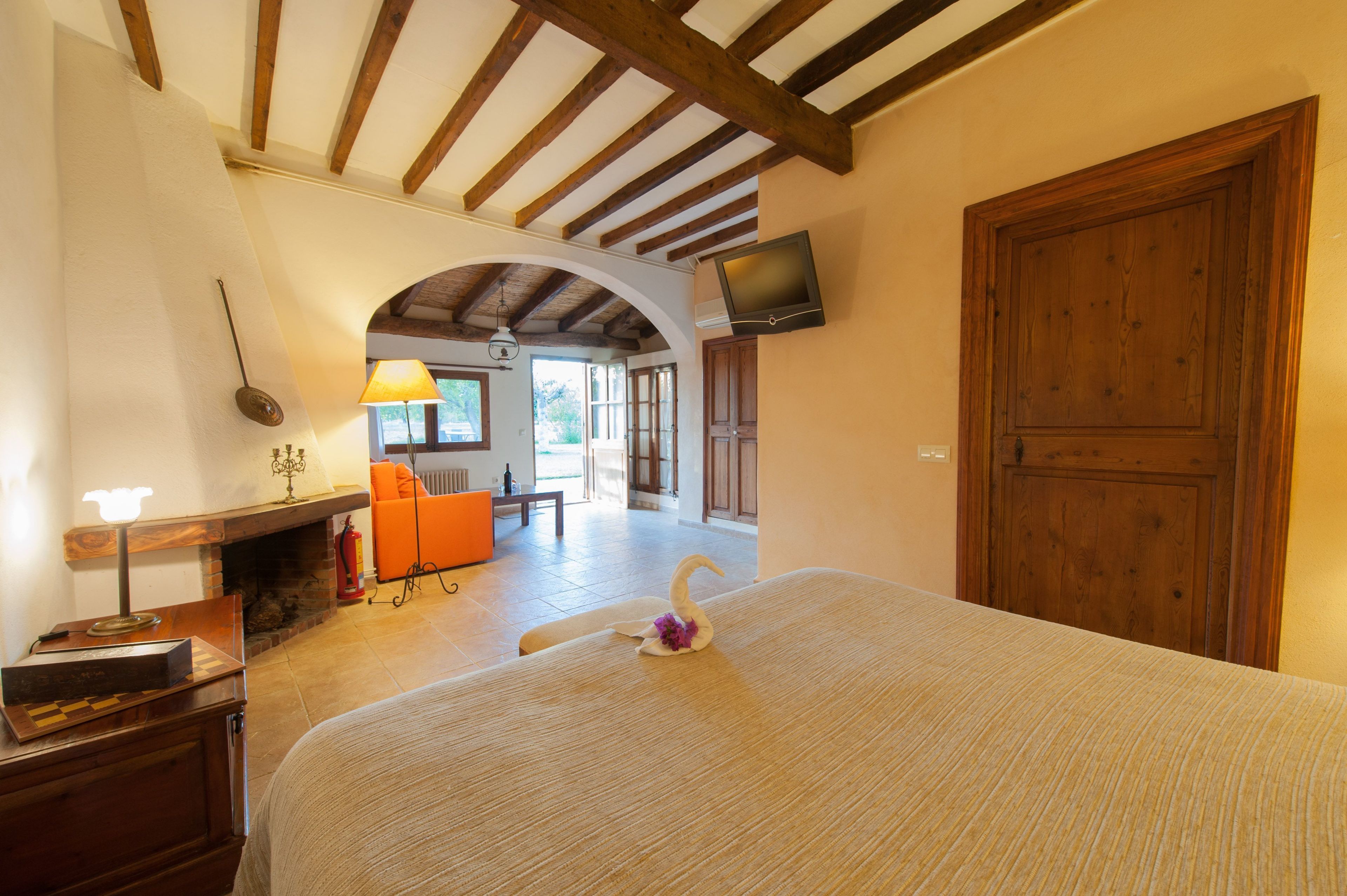 Una camera d'albergo con un letto, un caminetto, una televisione a parete e una porta ad arco che conduce a un'altra stanza.
