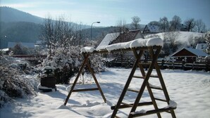 Two wooden ladders covered in snow, set against a backdrop of a snowy landscape with houses and trees. - Gasthaus Finken (Oppenau)