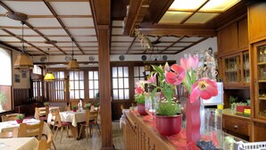 A traditional Japanese restaurant interior with wooden beams, tatami flooring, and a counter with potted plants and a small figurine. - Gasthaus Finken (Oppenau)