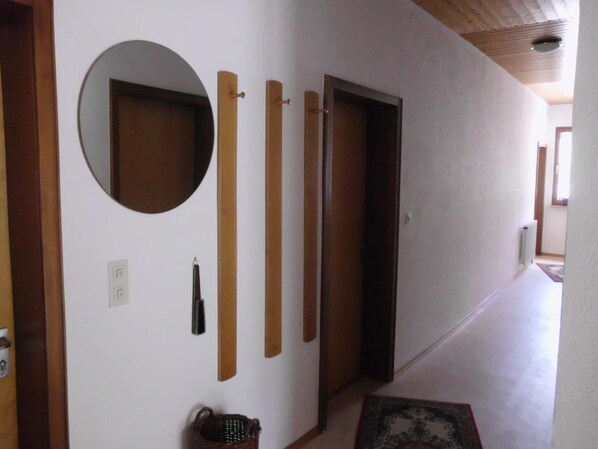A hallway with a wooden door, a round mirror, and several vertical wooden panels on the wall.