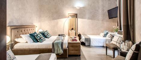 Una habitación de hotel moderna con una cama grande, una cama adicional, un sofá, un escritorio y una televisión.
