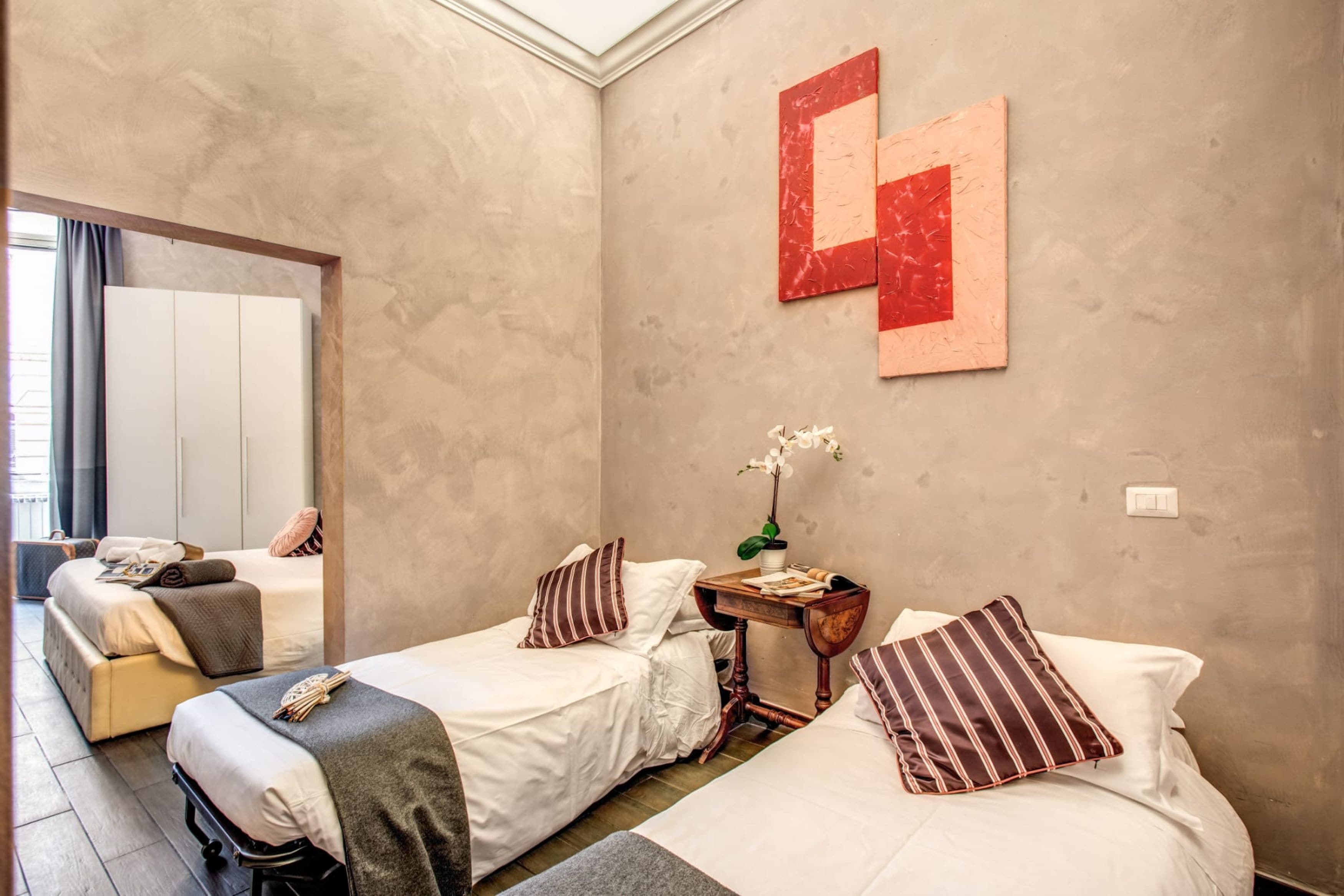 A hotel room with two beds, a small table with a potted plant, and a large mirror.