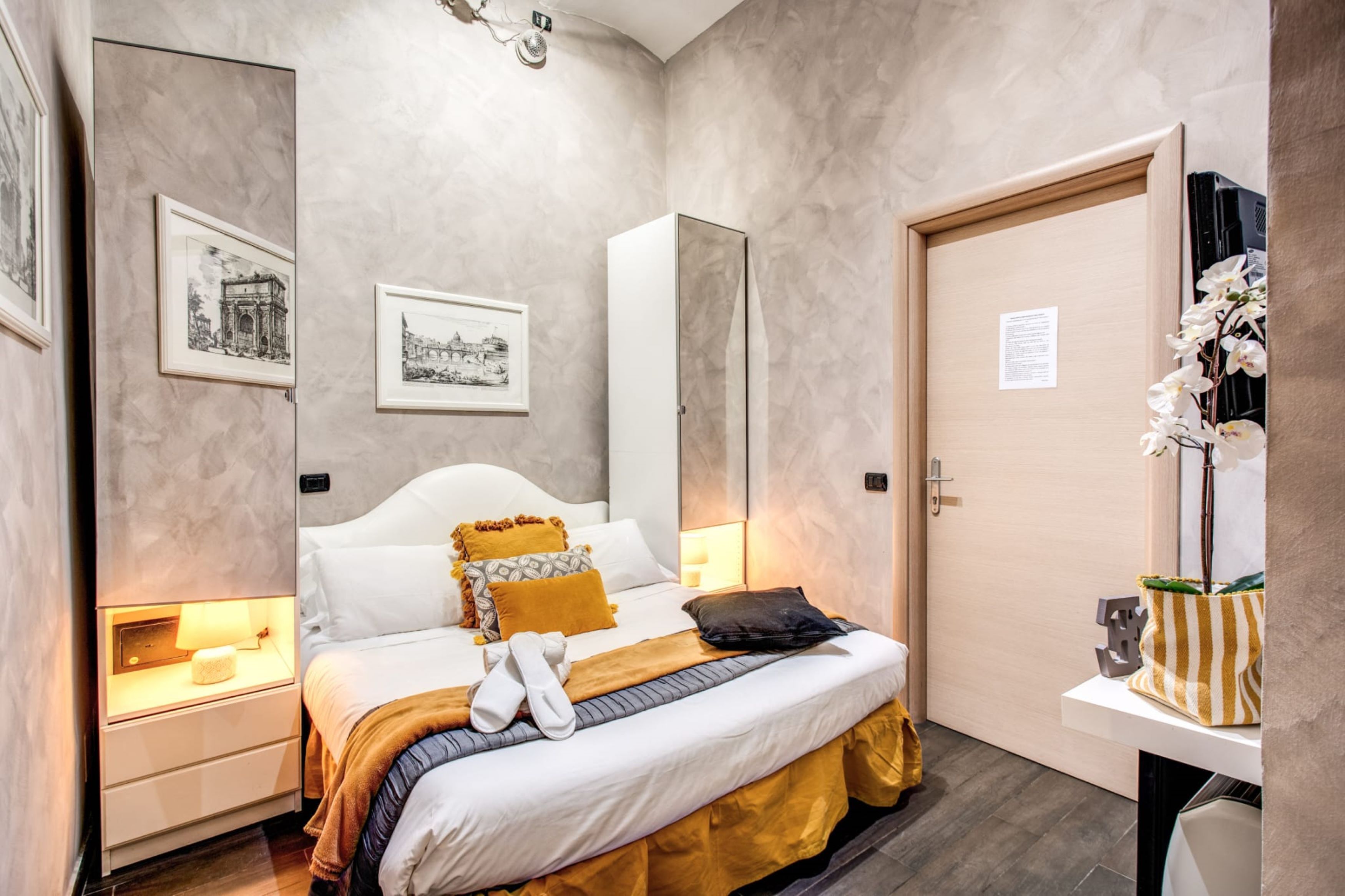 A bedroom with a bed, bedside tables, a mirror, and framed pictures on the walls.