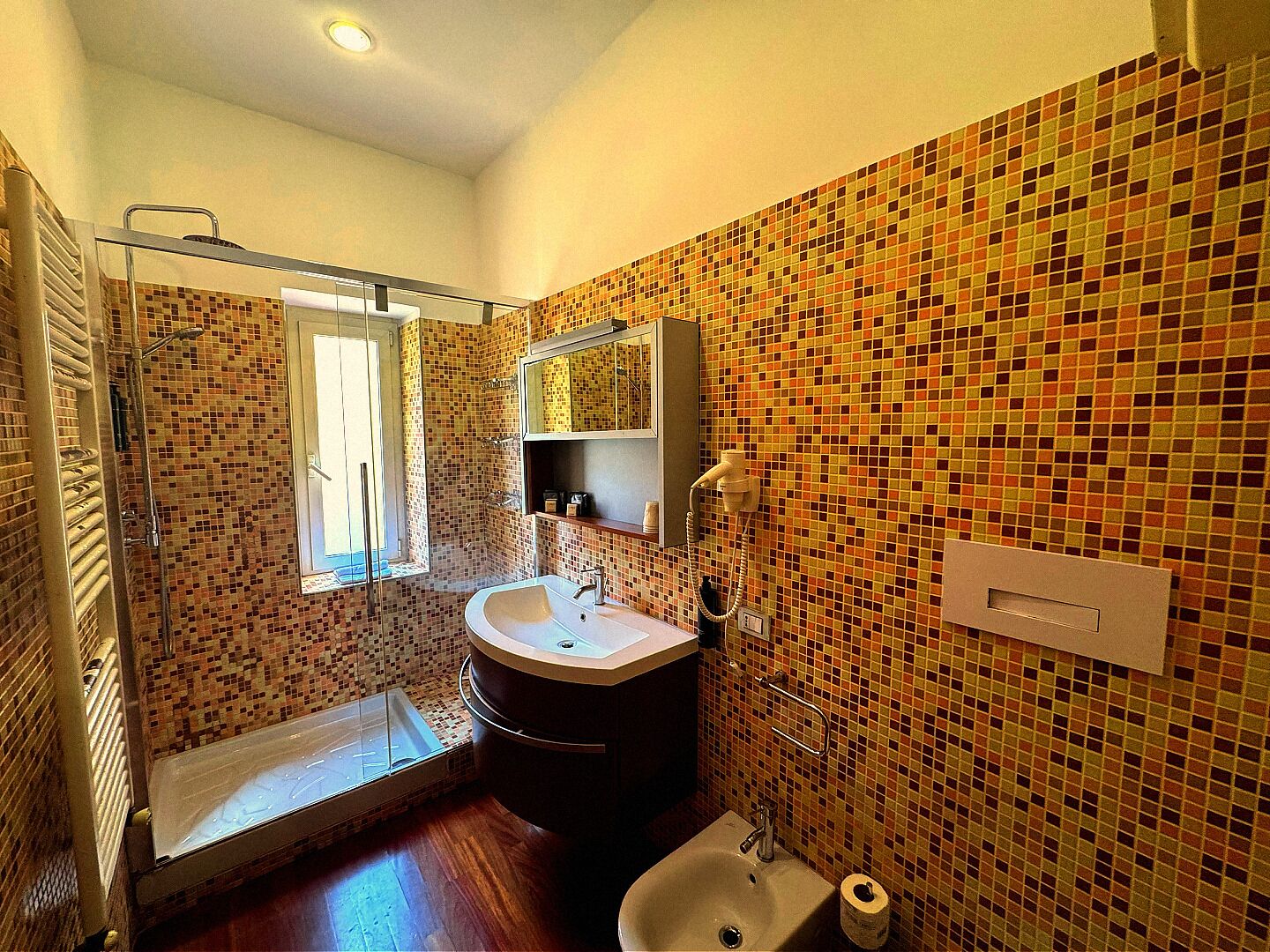 A bathroom with a shower, sink, toilet, and a mirror.