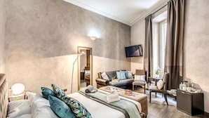 A modern hotel room with a large bed, a sofa, a TV, and a desk with a lamp. - La Residenza dell'Angelo (Rome)