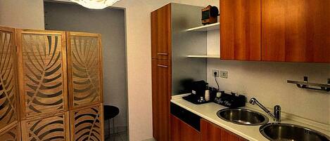 A kitchen with wooden cabinets, a sink, a coffee machine, and a pendant light.