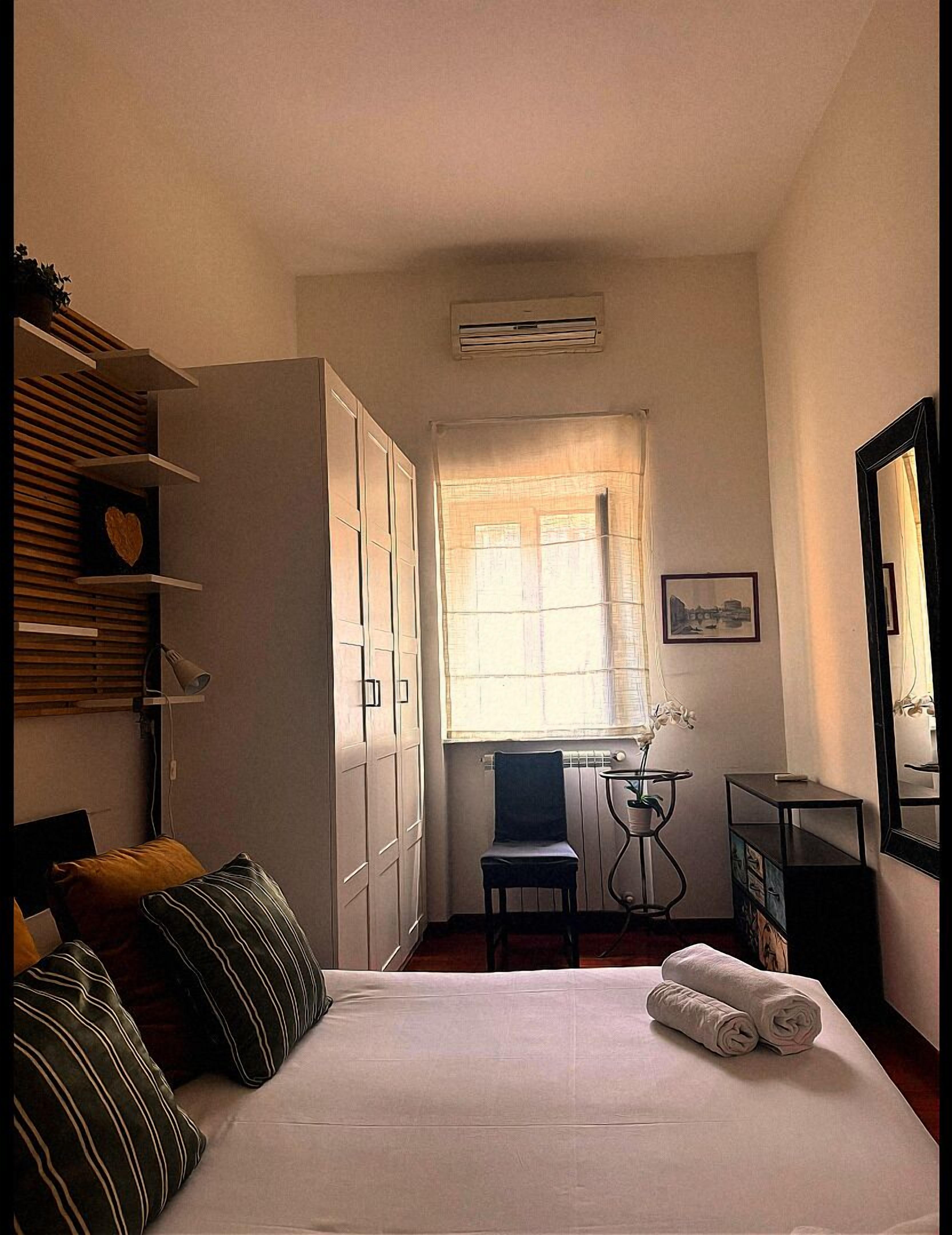 Un dormitorio con cama, una silla, un escritorio y un armario.