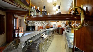 Eine Bar mit Holztresen, Gläsern und verschiedenen Flaschen.